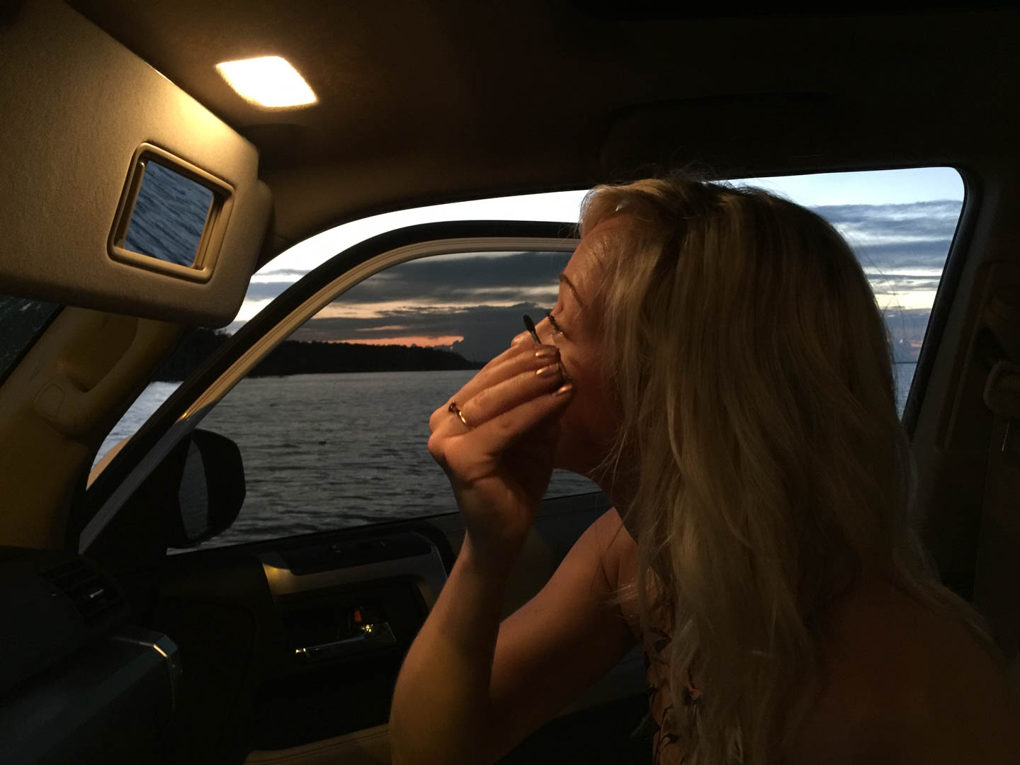Girl applying eyeliner while riding on a ferry.